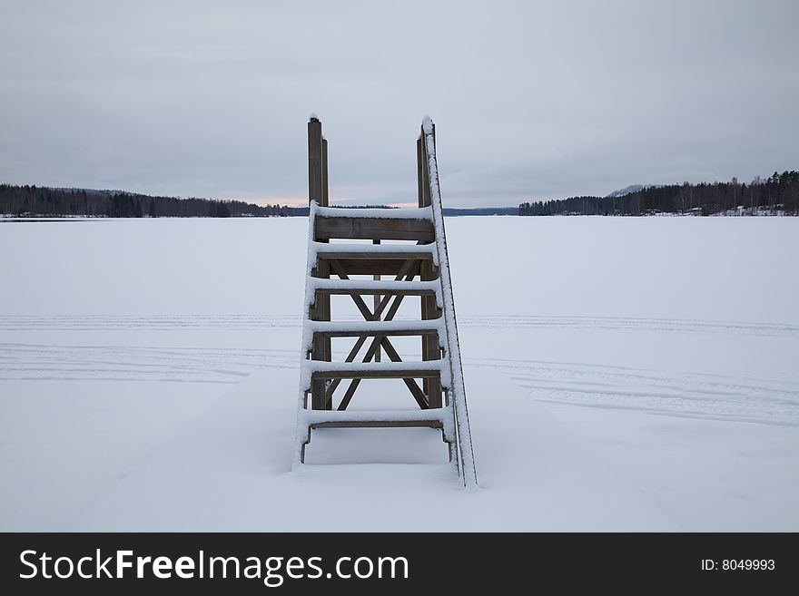 Wooden stairs at frozen lake. An empty landscape with stairs leading to nowhere. Wooden stairs at frozen lake. An empty landscape with stairs leading to nowhere.