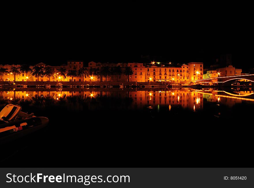 Mediterranean Town Along River Bank At Night.