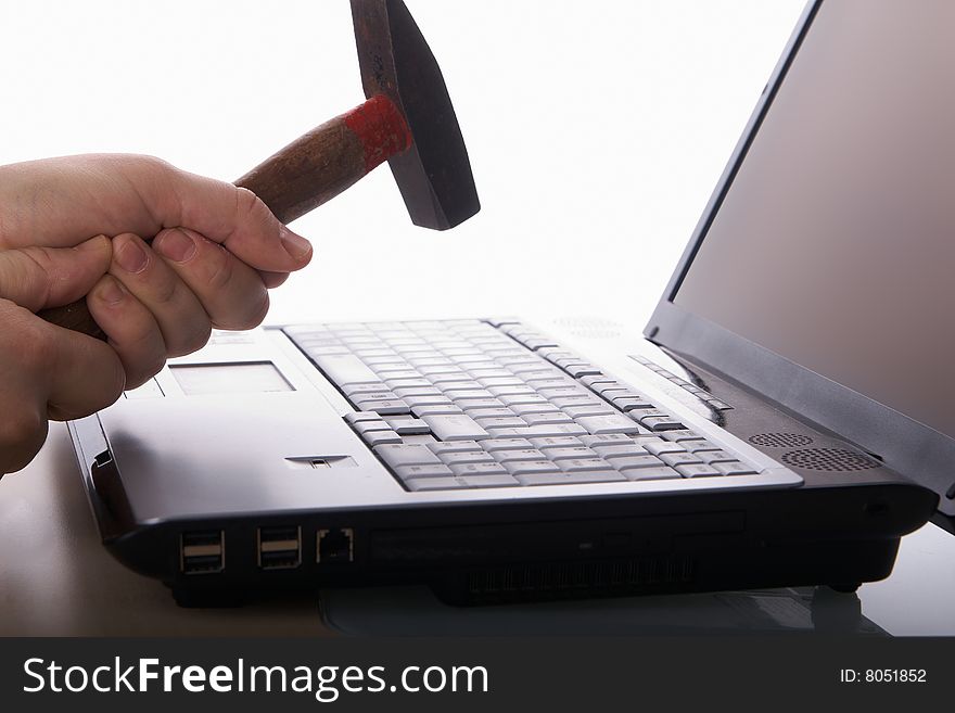 A hand hits a laptop with a hammer on a table. Isolated over white background. Copyspace also on the screen. A hand hits a laptop with a hammer on a table. Isolated over white background. Copyspace also on the screen.