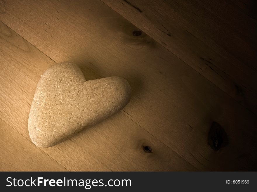 Heart shaped Stone on wooden Table in background.