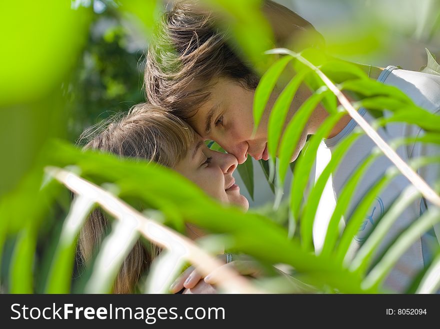 Young couple in the green bushes looking at each other
