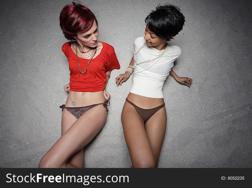 Two women looking at each other on the sand. Two women looking at each other on the sand