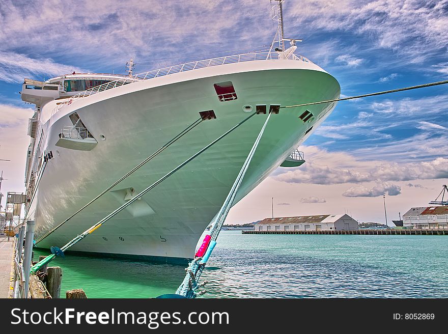 Luxury white cruise ship at harbor on a clear day with calm seas and blue sky