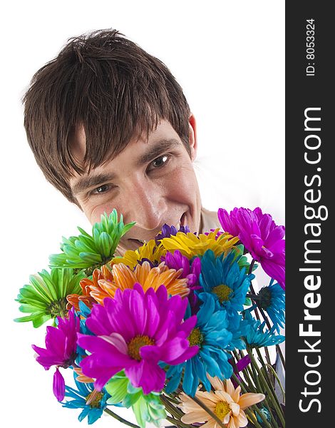 A young man holds very colorful flowers in front of him and peers from behind them. A young man holds very colorful flowers in front of him and peers from behind them