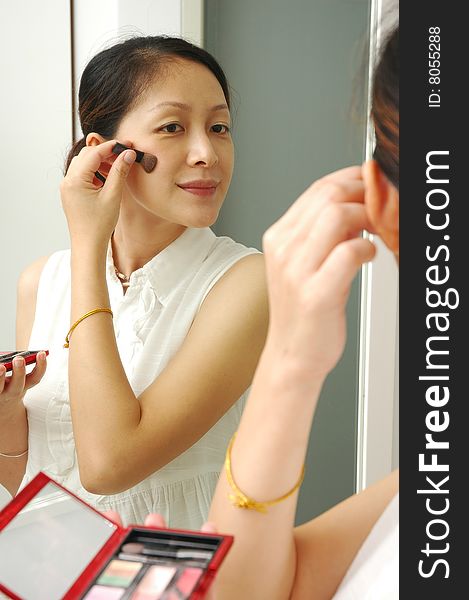 Chinese young lady make up in front of mirror