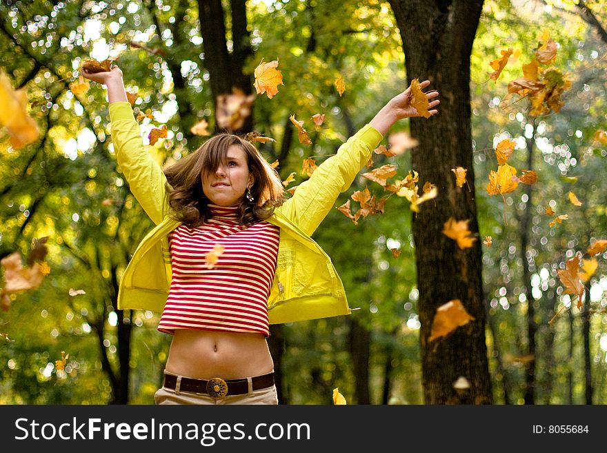 The girl in the park scatters yellow leaves. The girl in the park scatters yellow leaves