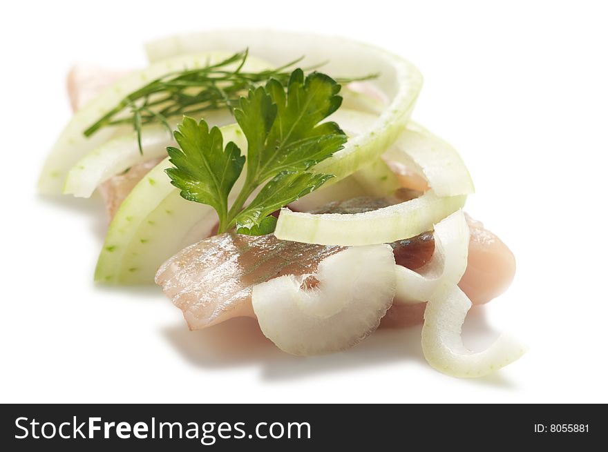 Pieces of herring with cut onion, dill, parsley isolated on a white background.