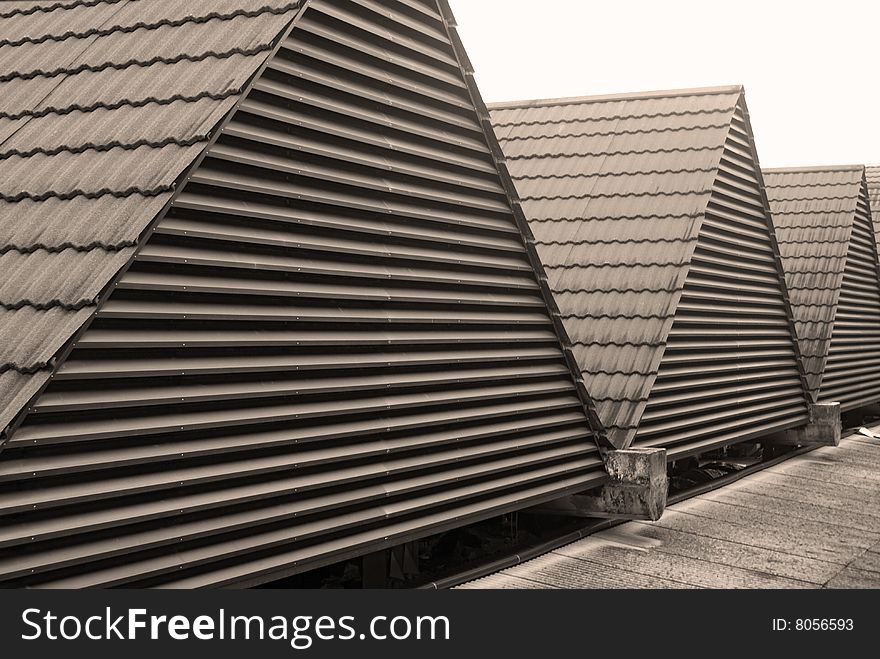 A row of triangular rooftops with fitted with ceramic tiles and metal railings.