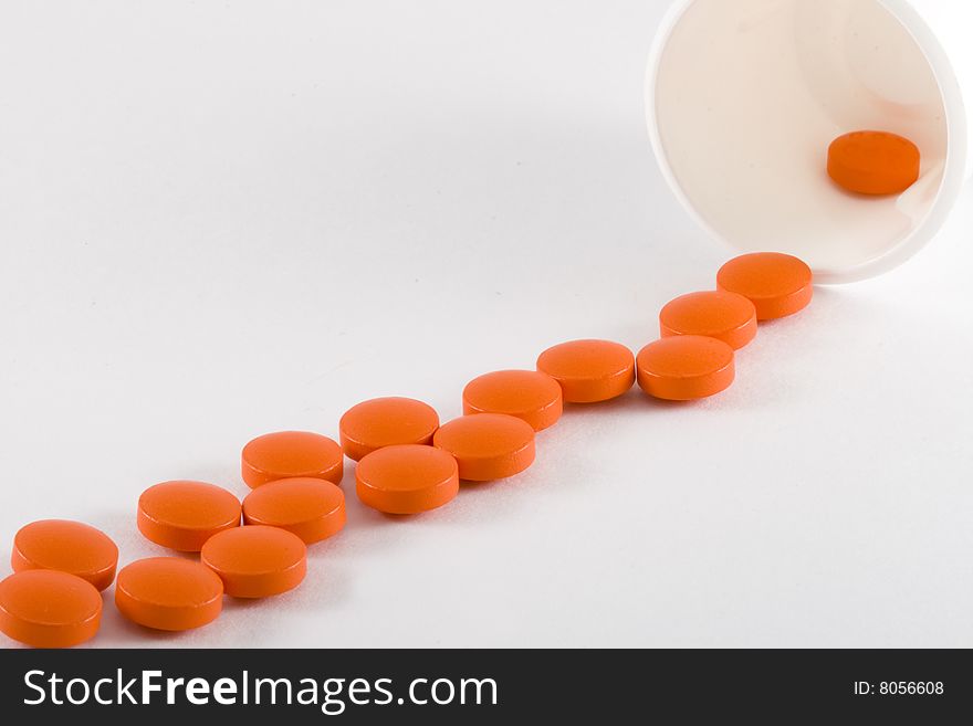 A row of spilt orange pills - close up. A row of spilt orange pills - close up