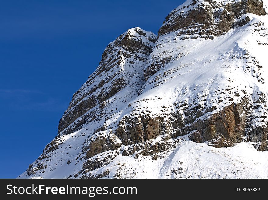 A view of a craggy cliff face covered in snow. A view of a craggy cliff face covered in snow