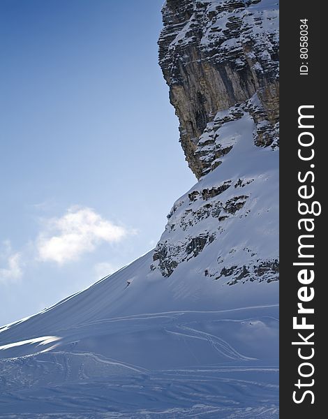 A view of a cliff face with some ski tracks below. A view of a cliff face with some ski tracks below