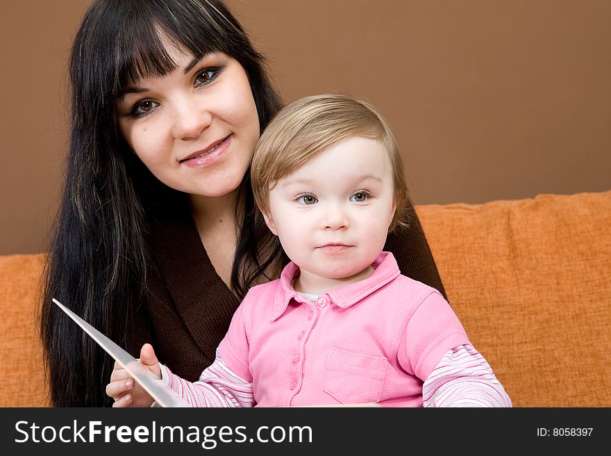 Mother and daughter sitting on sofa with book. Mother and daughter sitting on sofa with book