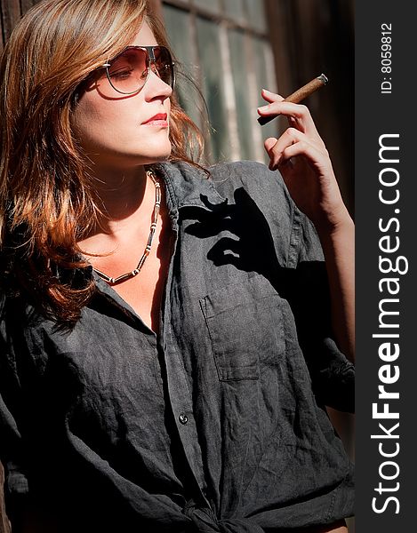 Young woman posing with cigar on sunny day