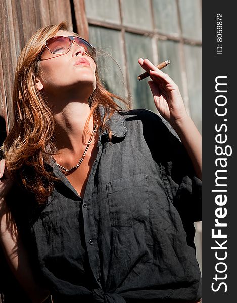 Young woman with sunglasses enjoying sun and cigar. Young woman with sunglasses enjoying sun and cigar