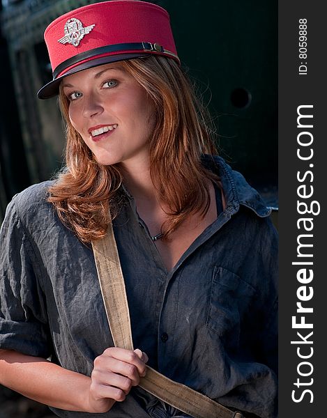 Smiling woman with red conductor's cap standing in front of locomotive