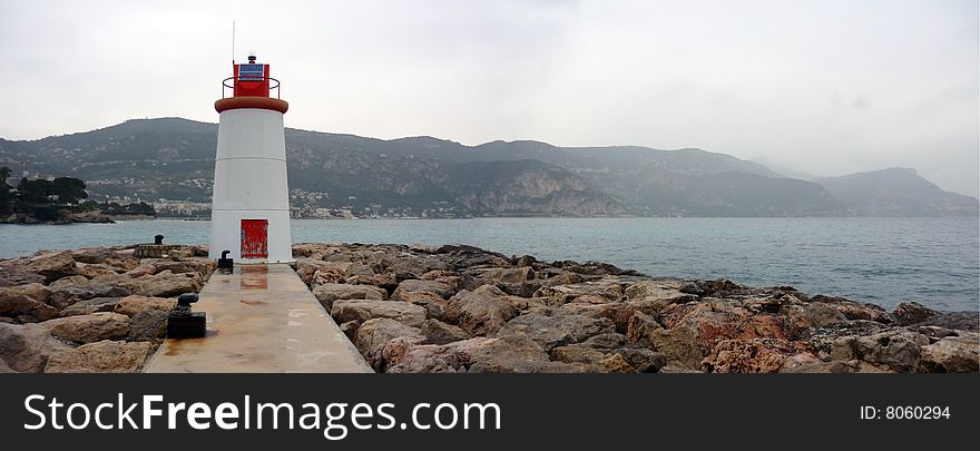 A light house on a pier overlooking the bay of Beaulieu on the Riviera. A light house on a pier overlooking the bay of Beaulieu on the Riviera
