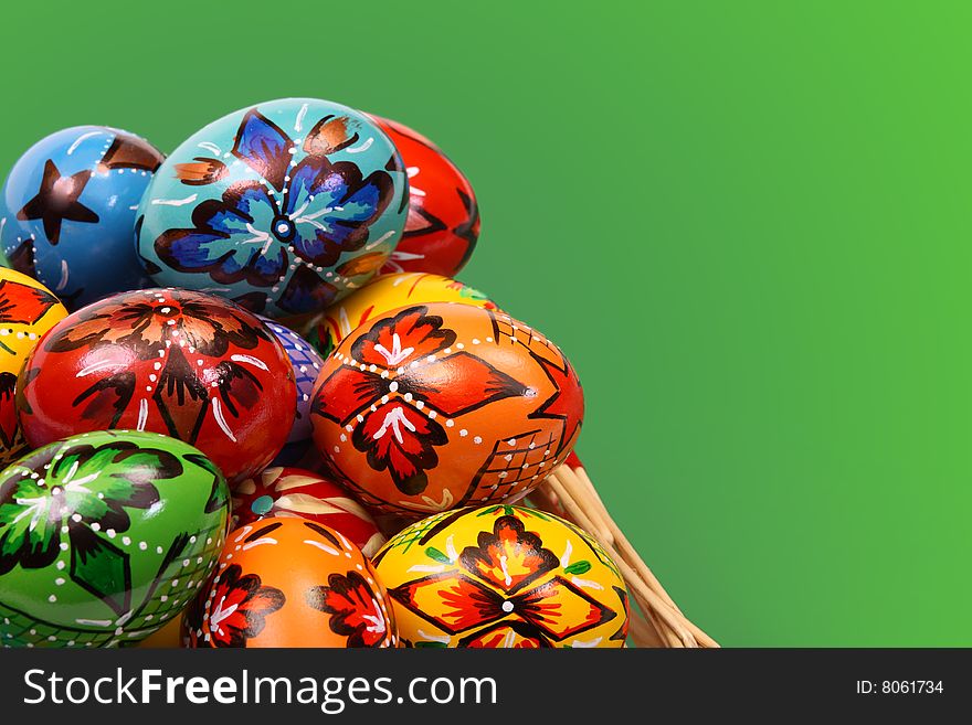 Colorful Easter Eggs in Basket on green background