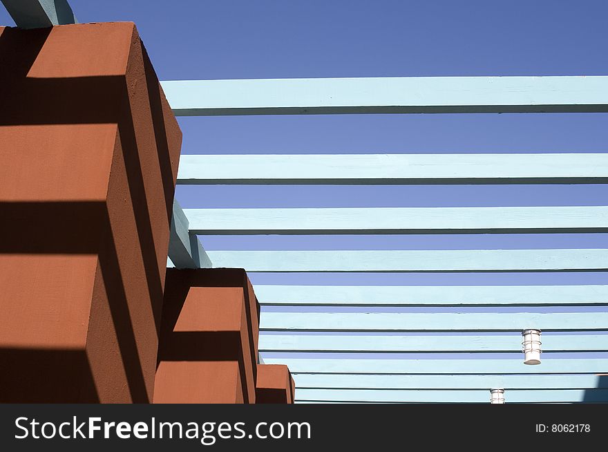 Abstract geometrical concept... Dark orange column and light blue wooden rows against blue sky. Abstract geometrical concept... Dark orange column and light blue wooden rows against blue sky...