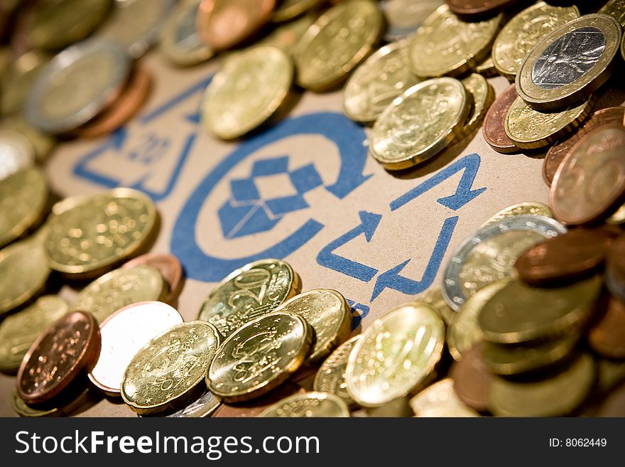 Recycling sign on cardboard with euro coins. Recycling sign on cardboard with euro coins