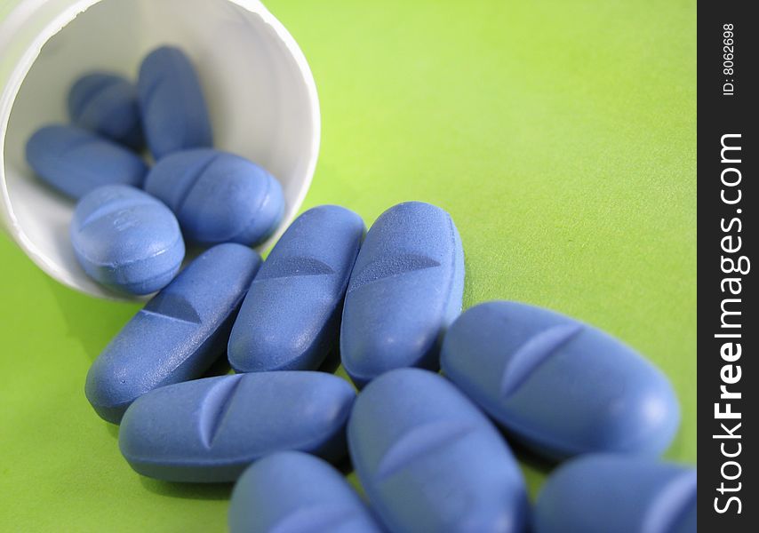 Blue pills spilled on green