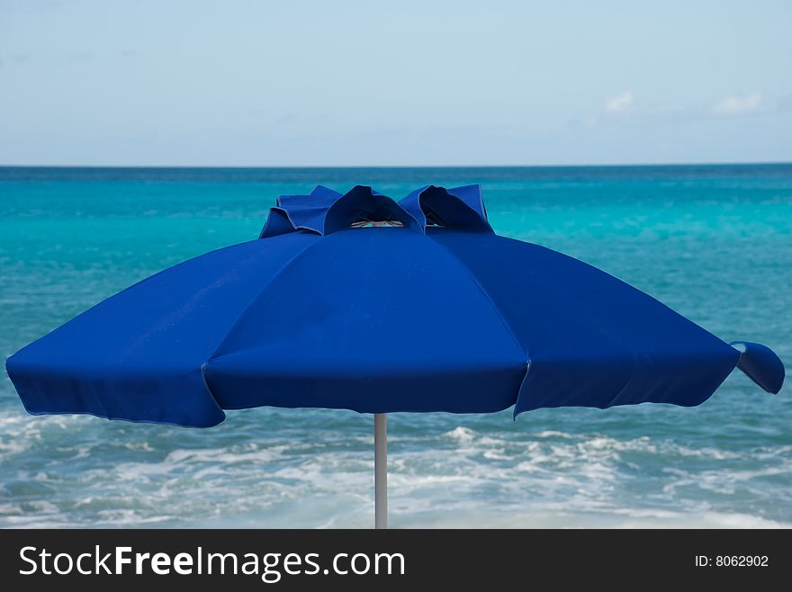 Blue umbrella on beach with tropical sea in the background. Blue umbrella on beach with tropical sea in the background.
