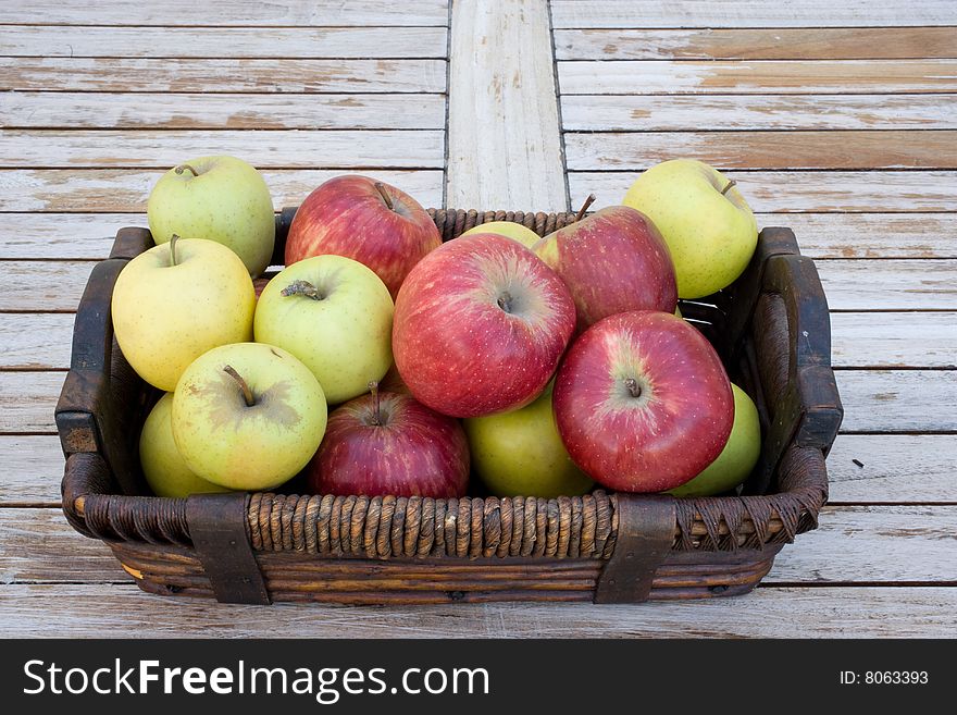 Yellow, green and red apples in a brown basket. Yellow, green and red apples in a brown basket