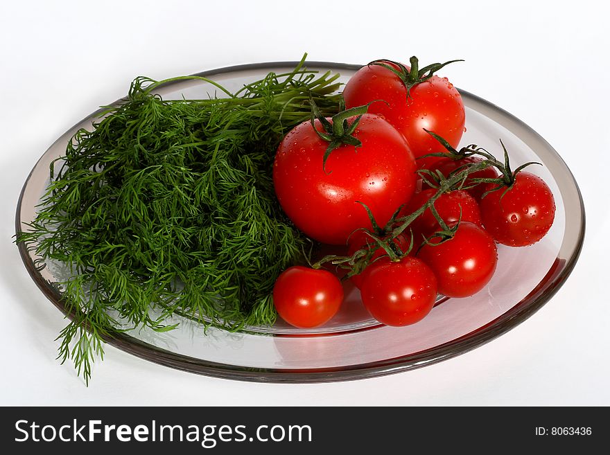 Tomatoes and dill on a plate isolated on white