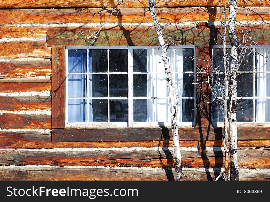 Window from a loghouse with a tree in front