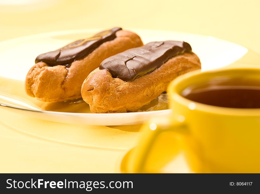 Chocolate pastry filled with custard for dessert and yellow cup. Chocolate pastry filled with custard for dessert and yellow cup