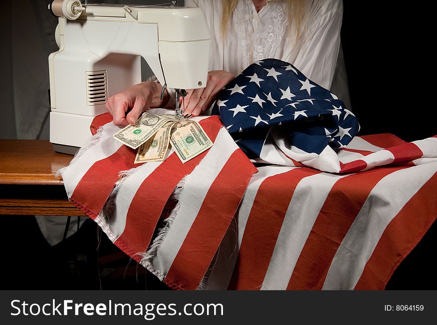 Close up of a woman sewing American money into the mending of a torn American flag on a sewing machine. Close up of a woman sewing American money into the mending of a torn American flag on a sewing machine.