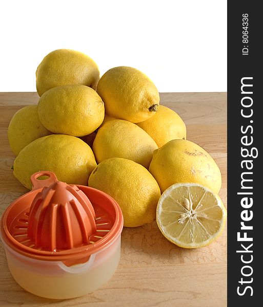 A number of home-grown, organic lemons and manual juicer on a wooden surface against white background,. A number of home-grown, organic lemons and manual juicer on a wooden surface against white background,