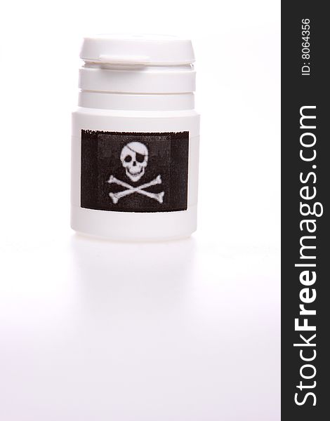 White pillbox isolated on white with copy space, Black label with skull and bones on the pillbox. White pillbox isolated on white with copy space, Black label with skull and bones on the pillbox