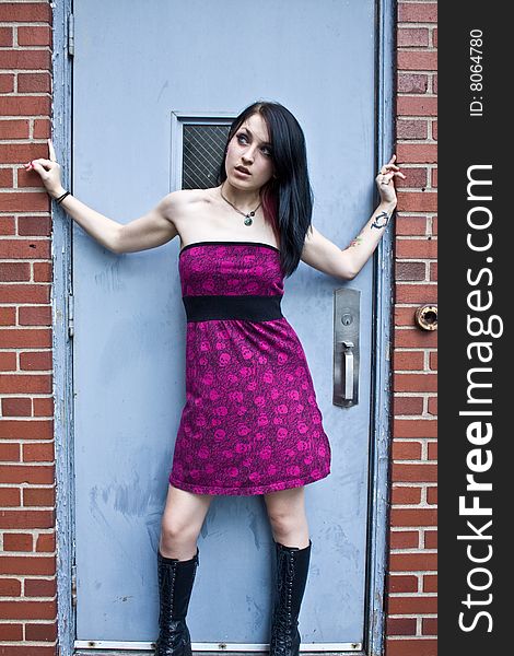 Pretty woman with jet black hair wearing a purple sleeveless dress and high boots looking upward. Pretty woman with jet black hair wearing a purple sleeveless dress and high boots looking upward