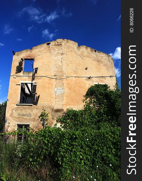 Backside of an old abondoned burnt down farmhouse in italy, plants are growing over it. Backside of an old abondoned burnt down farmhouse in italy, plants are growing over it