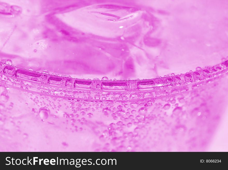 Pink soda water with the ridge of the cup and bubbles as the focal point.