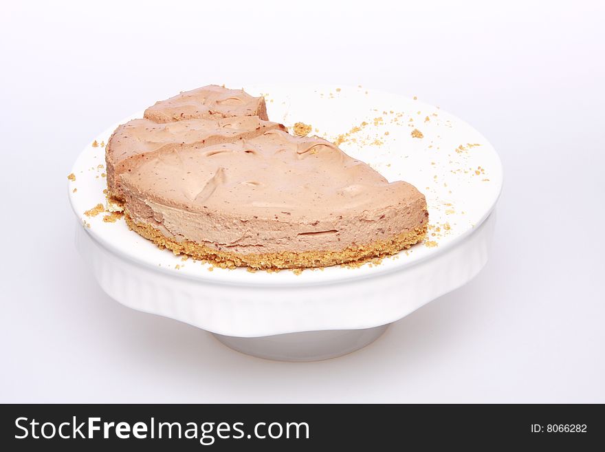 Half finished sliced chocolate cheesecake isolated on white with plenty of crumbs