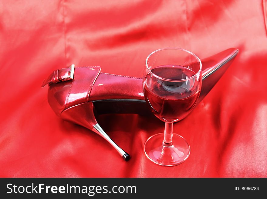 Red wine and shoe on red satin background. Red wine and shoe on red satin background