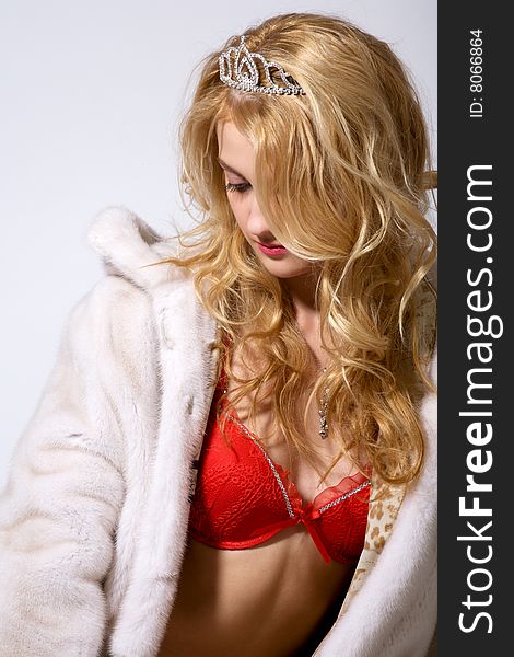 Portrait of young woman in white fur coat and red lingerie on grey. Portrait of young woman in white fur coat and red lingerie on grey