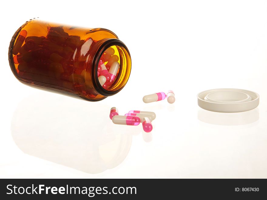 Pills spilling from a pill bottle, isolated on white with copy space. High key lighting. Pills spilling from a pill bottle, isolated on white with copy space. High key lighting