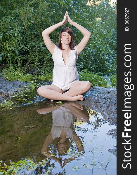 Woman in yoga position near a pond