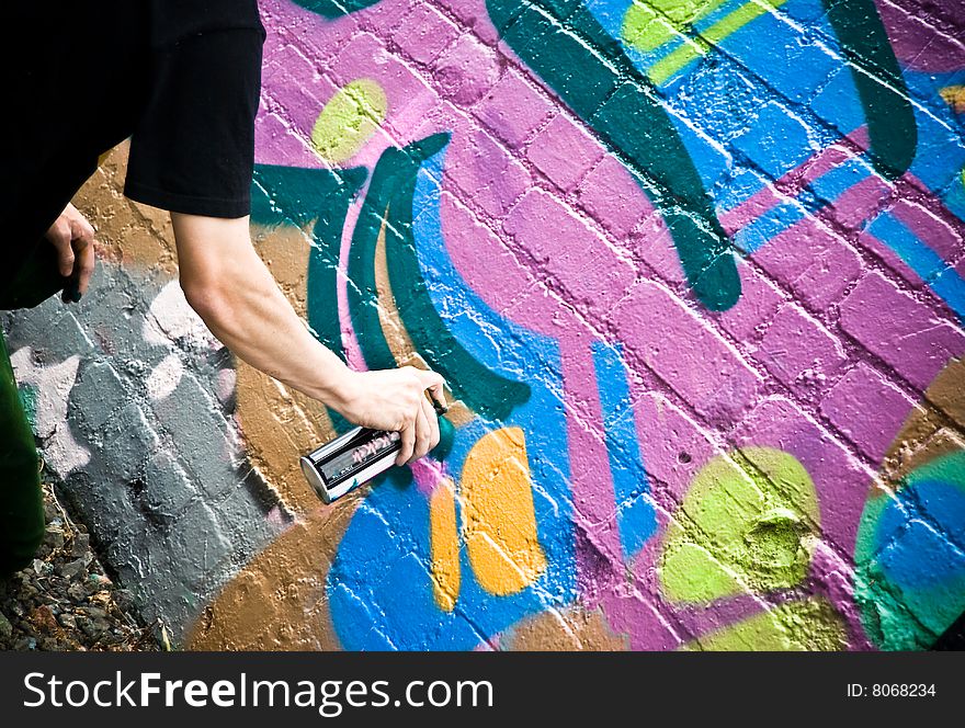 Graffiti Artist At Work spraying on a textured brick wall downtown Auckland.