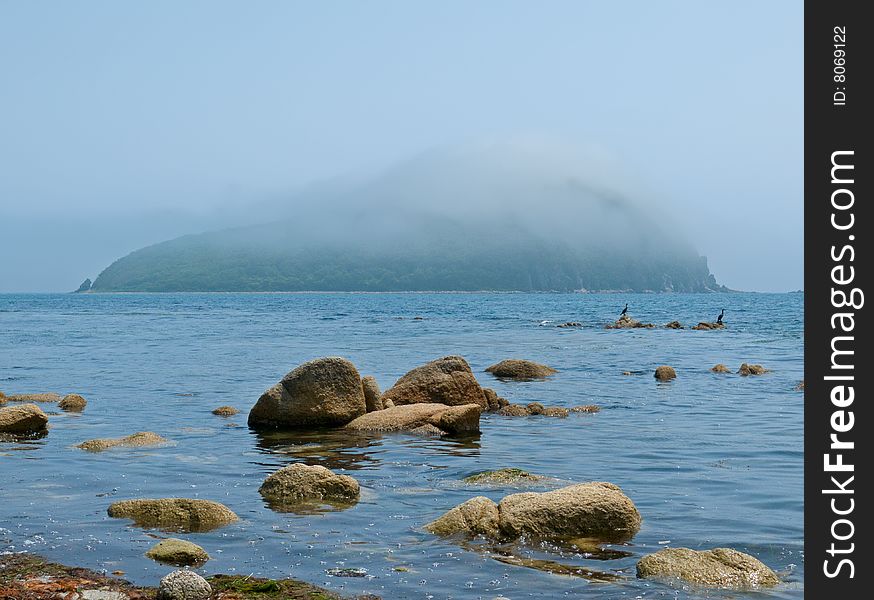 The stones in seawater and small green island. The stones in seawater and small green island.