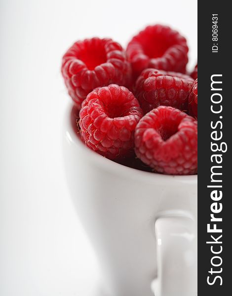 Raspberries in white cup, white background