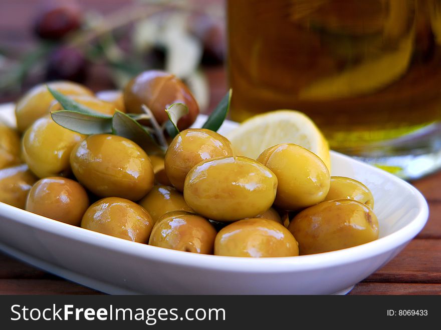 Fresh green olives and lemon in the plate