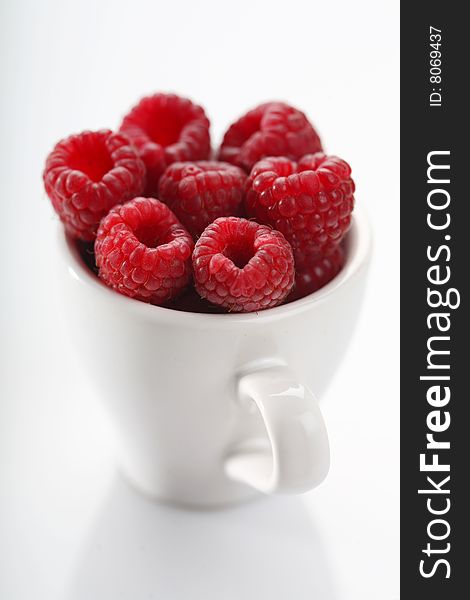 White cup of few raspberries