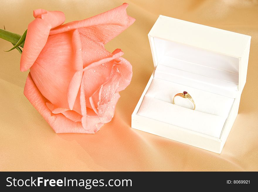 Beautiful rose and golden ring in gift box on silk backgroung. Beautiful rose and golden ring in gift box on silk backgroung