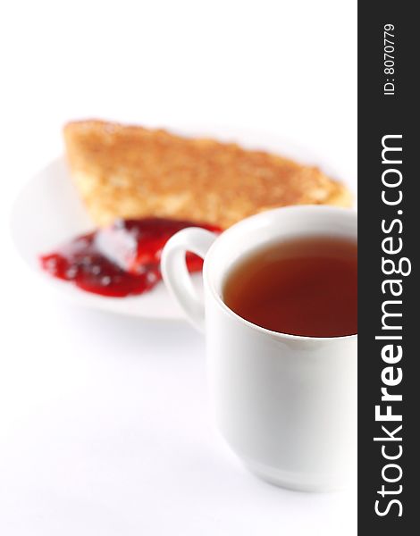Pancake with red jam on dish and tea cup