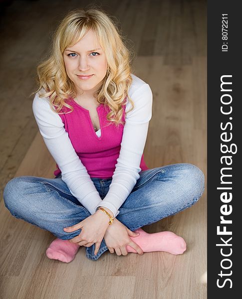 Fair-haired girl in jeans a white blouse sits on a floor. Fair-haired girl in jeans a white blouse sits on a floor