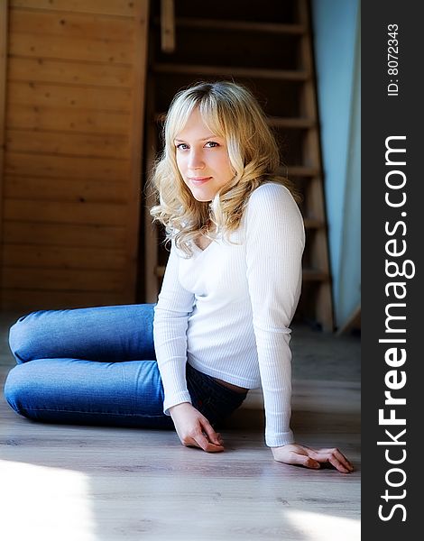 The fair-haired girl in jeans sits on a floor