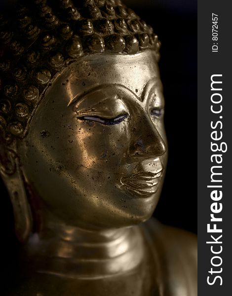 Close up of a gold Buddha statue in a dimly lit room. Close up of a gold Buddha statue in a dimly lit room.